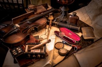 Vintage still-life of an antique desk: violin, eyeglasses, ink bottle, pocket watch, and scattered papers with a red-lined case nearby, in warm lighting.