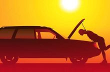 Silhouette of a person pushing a car with its hood up at sunset sunlit orange sky.